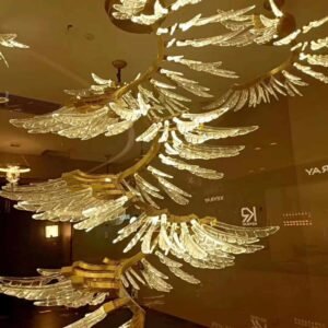 A stunning glass chandelier featuring gracefully flowing wings made from intricately designed glass parts. The delicate shapes reflect warm golden light, enhancing the elegance of the chandelier. Each wing showcases unique textures and handcrafted details, exemplifying superior craftsmanship. The soft glow created illuminates the surrounding space, adding a luxurious ambiance.