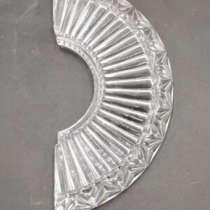 A beautifully crafted glass lamp base features a fan-shaped design, showcasing ridged textures and sharp-edged patterns that catch light beautifully. The glass is clear with an intricate design, highlighting the craftsmanship and unique characteristics typical of pressed glass manufacturing. Ideal for pairing with lamp fixtures, this piece adds elegance and functionality to interior decor.
